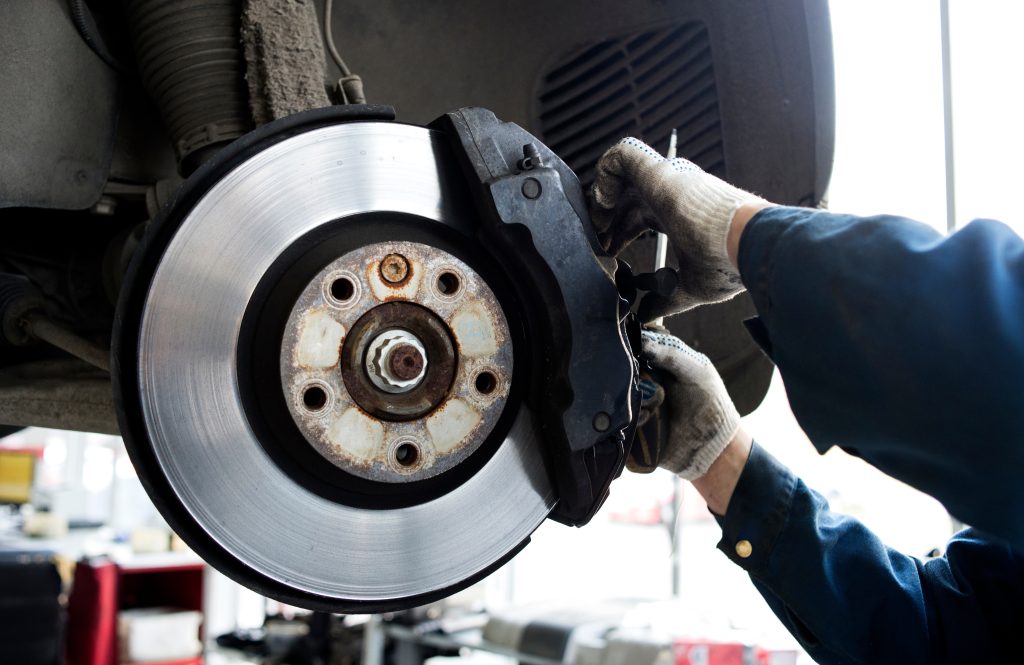 A mechanic working on a vehicle's brake pads. - Jim Turner Chevrolet McGregor, TX