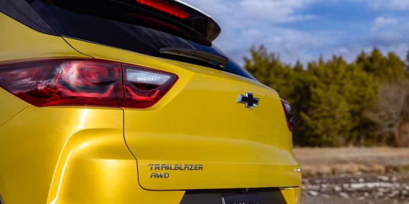 The rear exterior of an all-new Yellow 2024 Chevy Trailblazer parked in front of some trees. - Jim Turner Chevrolet McGregor, TX