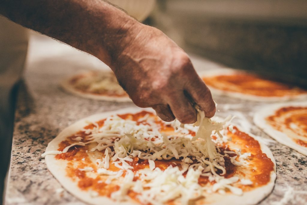 A pizza being prepared with cheese before going into the over. - Jim Turner Chevrolet McGregor, TX