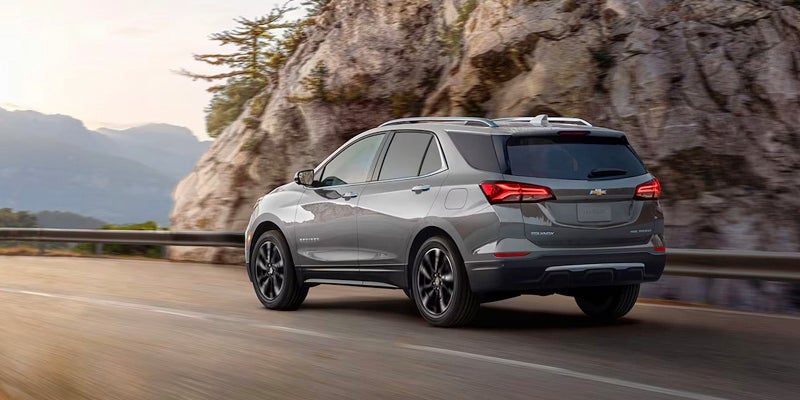 An all-new Gray 2024 Chevrolet Equinox driving on a mountainous higway. Jim Turner Chevrolet McGregor, TX